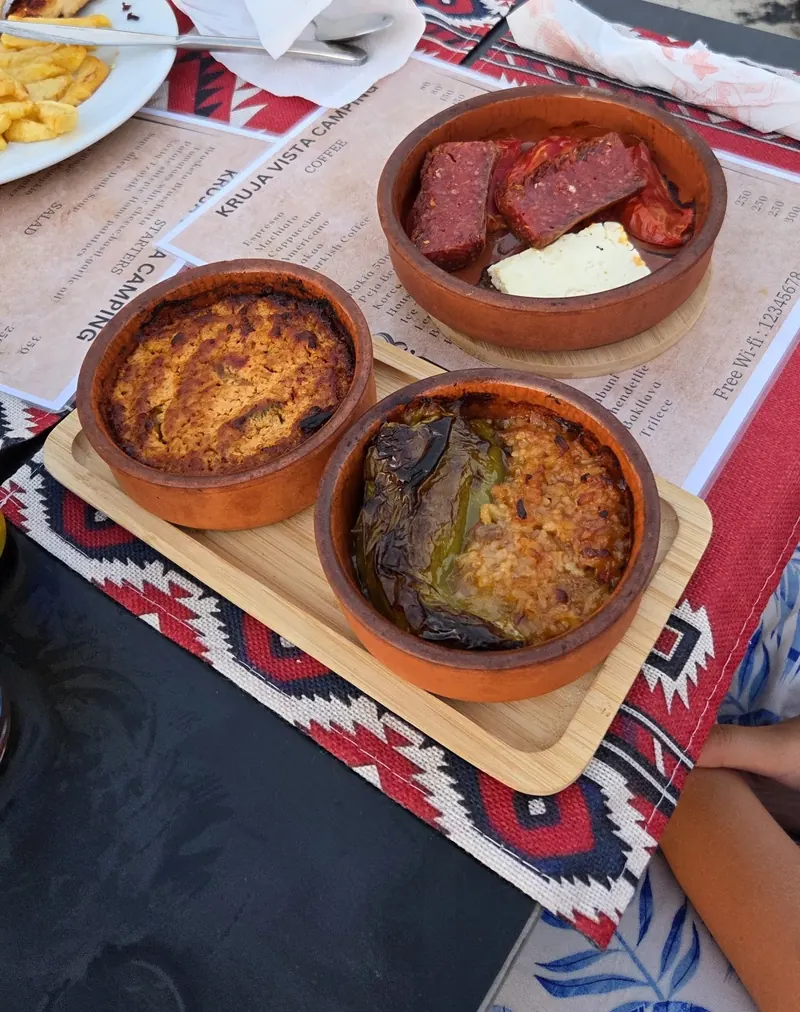 Three clay-pot dishes on a wooden board, served on the terrace above the olive trees