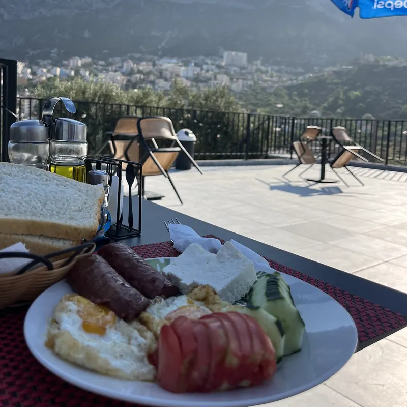 Breakfast of eggs, sausages, white cheese and tomatoes on the terrace, Krujë behind
