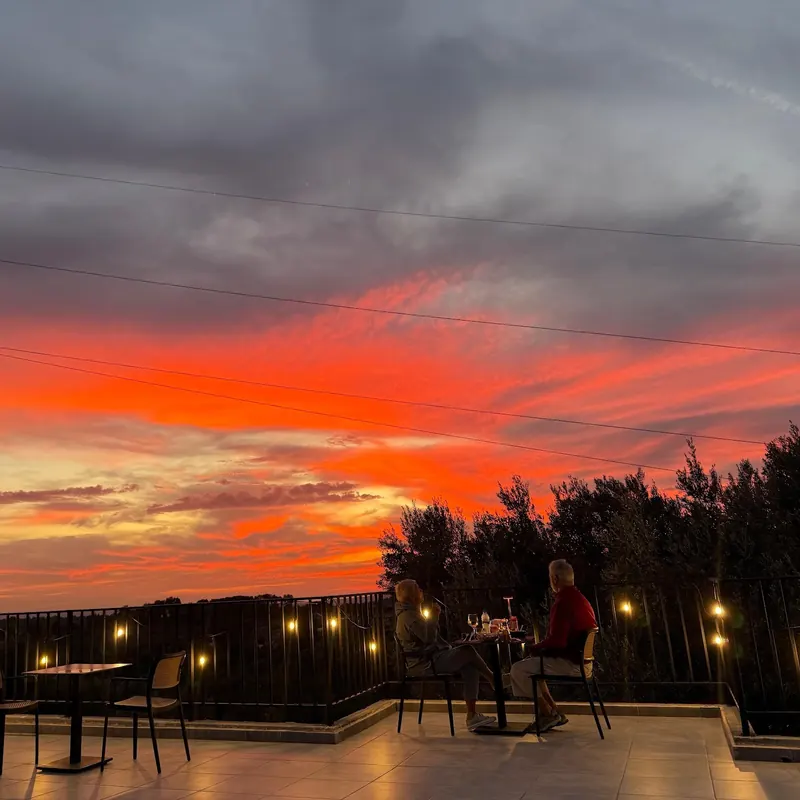 A fiery orange sunset over the rooftop terrace and its string lights