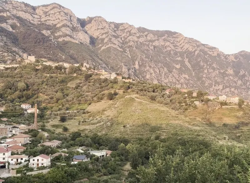 The hillside of Krujë at dusk, with the old town under the rock face