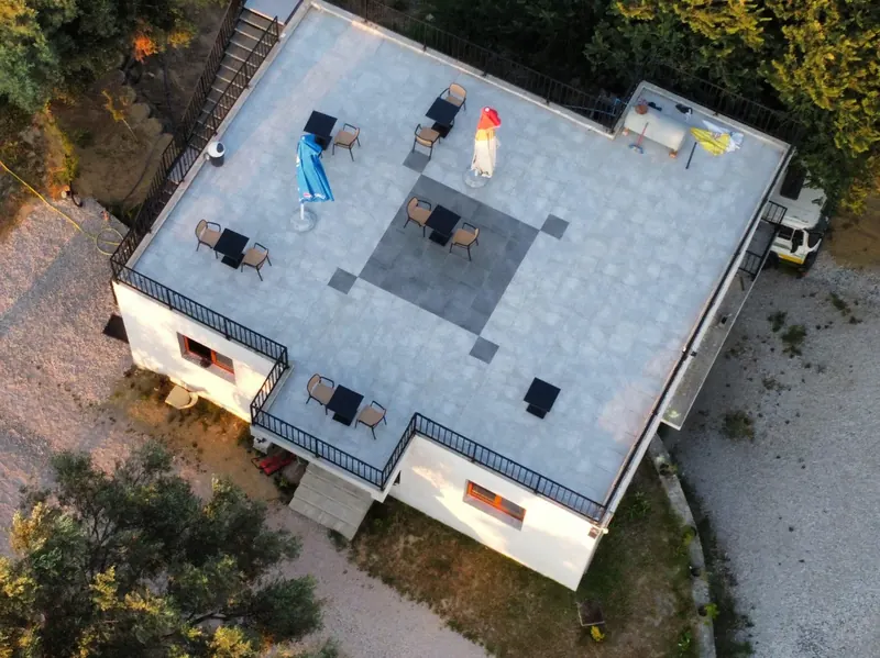 Aerial view of the guesthouse and its tiled rooftop terrace among the olive trees